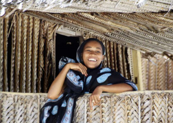 Lachende Frau vor einer Hütte auf Sansibar