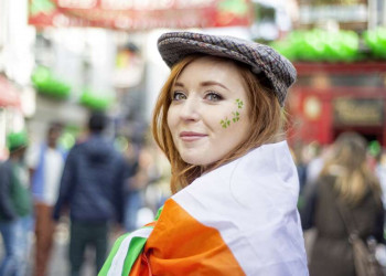 Eine irische Frau mit einer Irland-Flagge und Kleeblatt-Gesichtsbemalung am St. Patricks Day