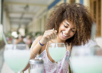 Fröhliche junge Kubanerin mit Cocktailglas