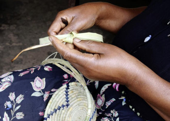 Korbflechterin auf einem Markt in Uganda